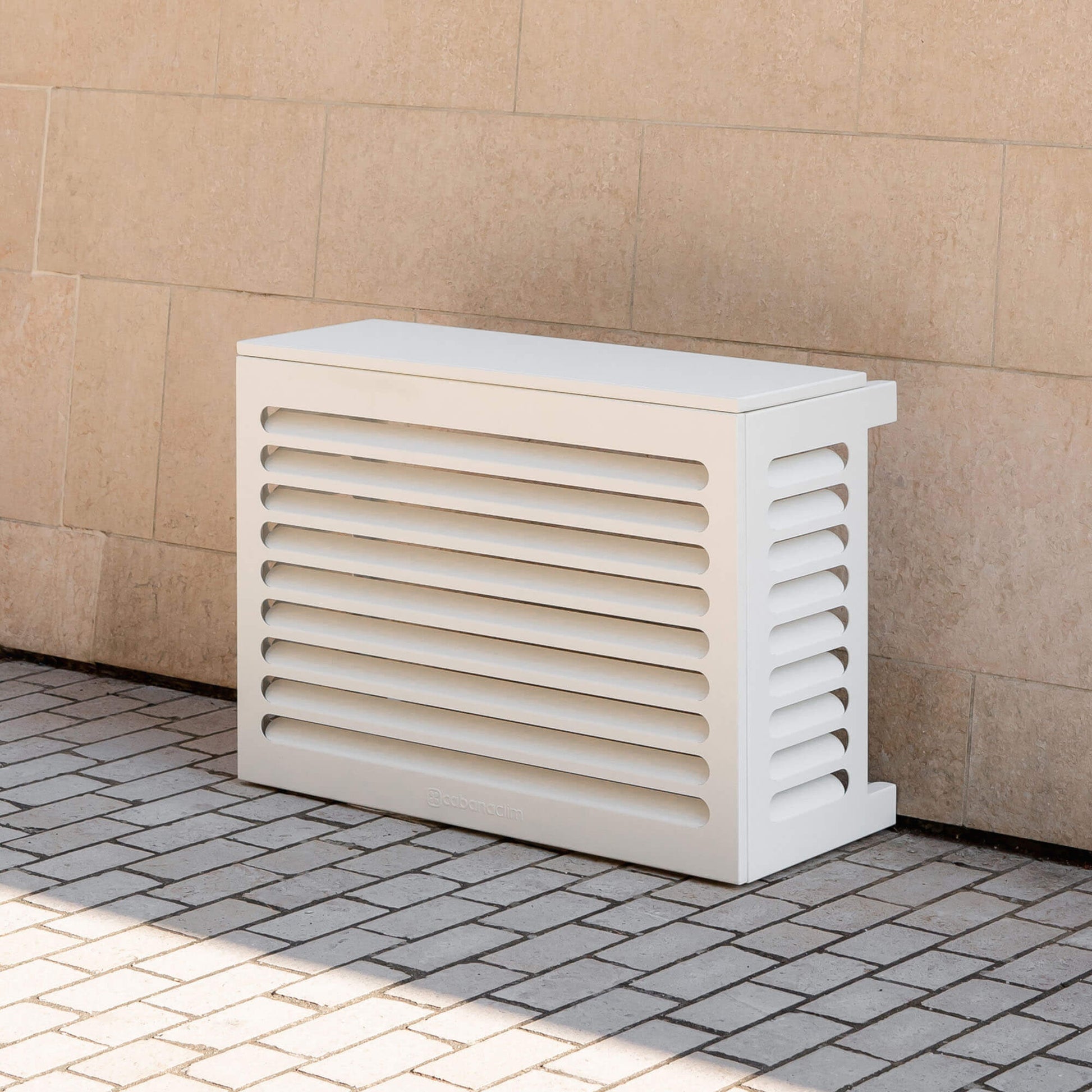Cache clim blanc (RAL 9010) pour climatiseur ou pompe à chaleur – taille XS – vue de face extérieure sur fond de mur clair, design contemporain en aluminium, persiennes pour ventilation optimale