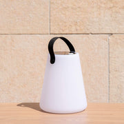 Lampe solaire d’extérieur blanche avec poignée noire, posée sur une table en bois en plein soleil